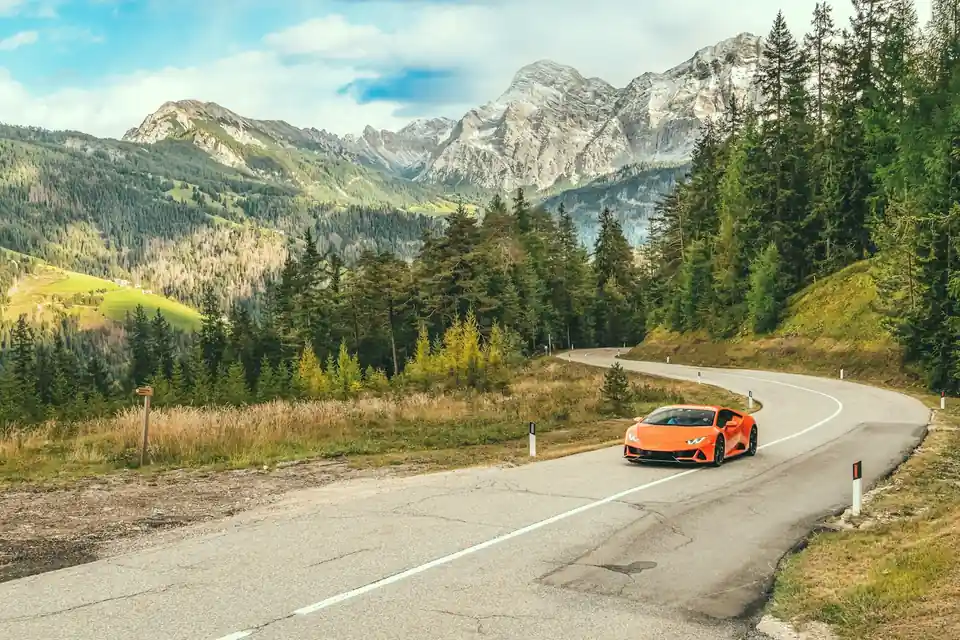 Auto sportiva arancione su una strada di montagna